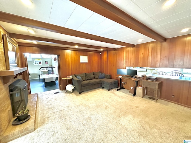 living room featuring light carpet, beam ceiling, and wood walls