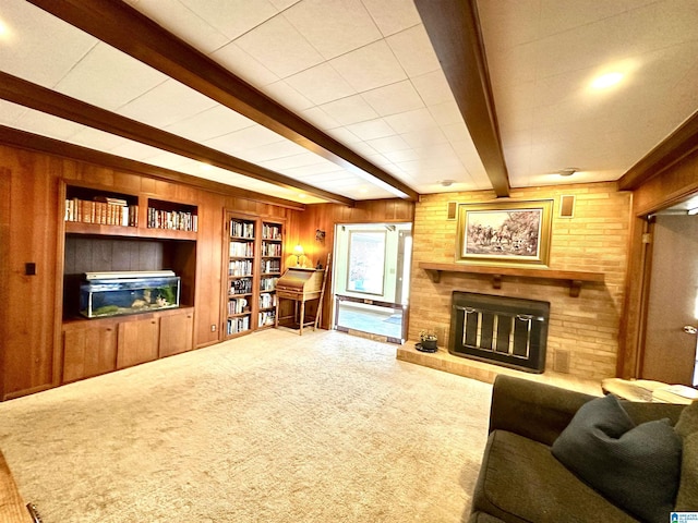 living room featuring beam ceiling, carpet, a brick fireplace, and wood walls