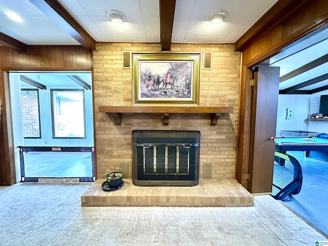 unfurnished living room with carpet flooring, a fireplace, beam ceiling, and wood walls