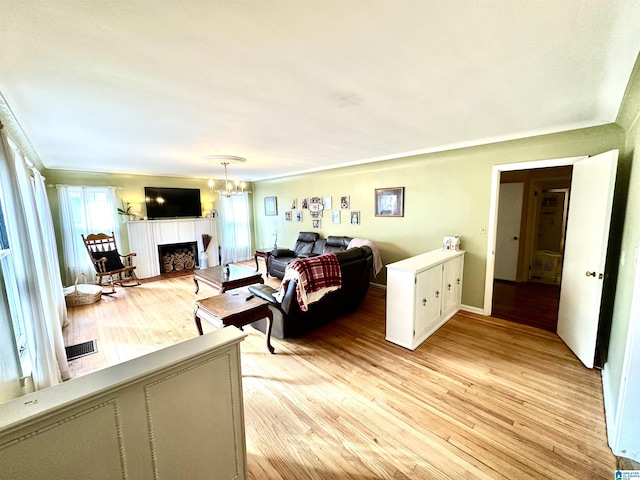 living room with an inviting chandelier, light hardwood / wood-style floors, and a tile fireplace