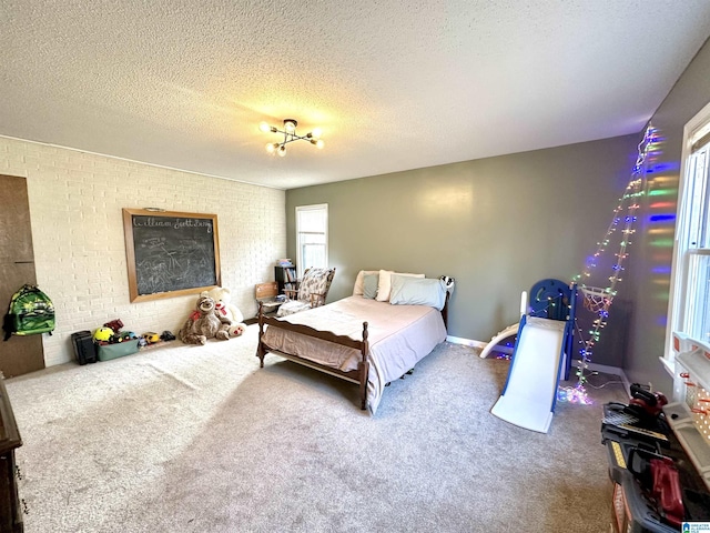 carpeted bedroom featuring a textured ceiling and brick wall