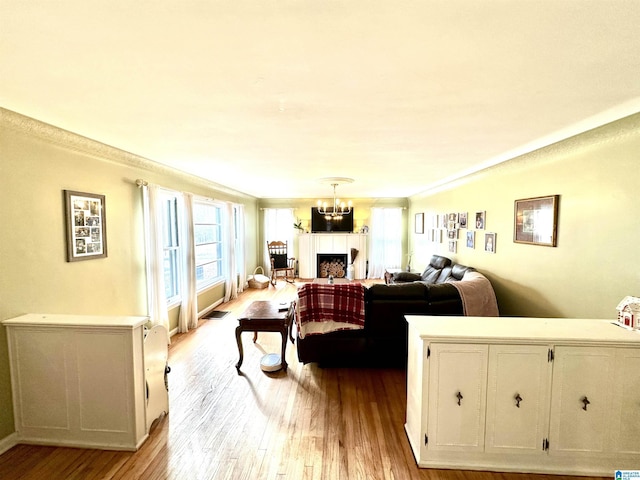 living room featuring crown molding, a chandelier, and light wood-type flooring