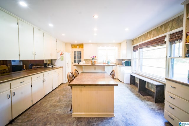 kitchen featuring white refrigerator, white cabinetry, and a kitchen island