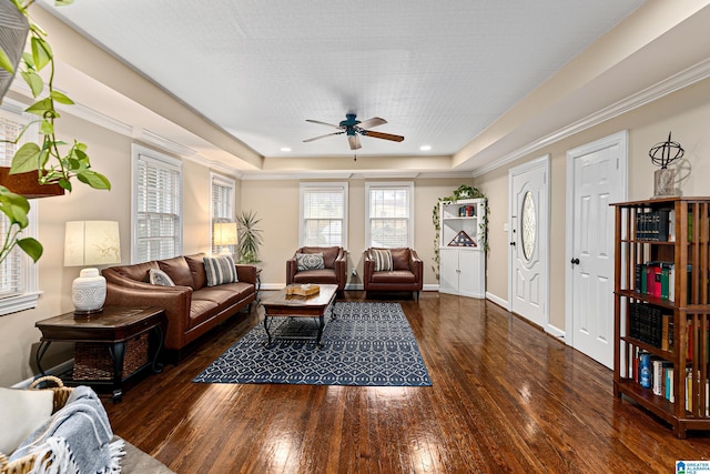 living room with dark hardwood / wood-style floors, ceiling fan, and a tray ceiling