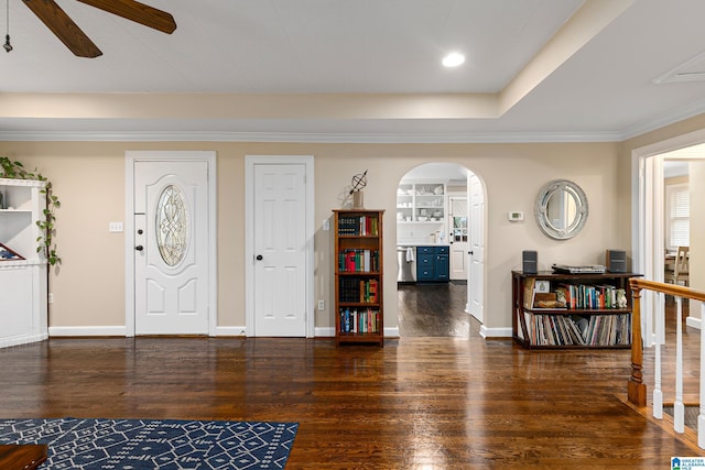 foyer entrance featuring dark wood-type flooring, ceiling fan, and a tray ceiling