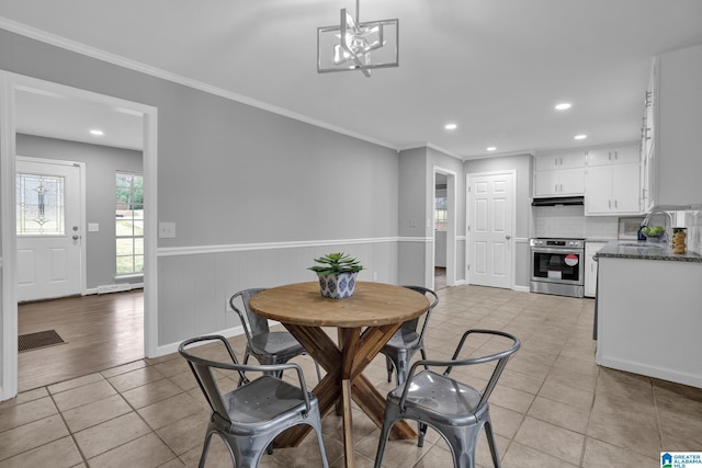 dining room with crown molding, sink, light tile patterned floors, and a chandelier