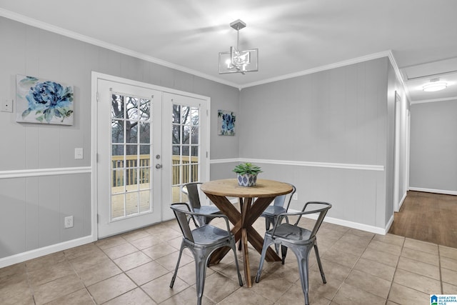 tiled dining room with french doors, ornamental molding, and an inviting chandelier