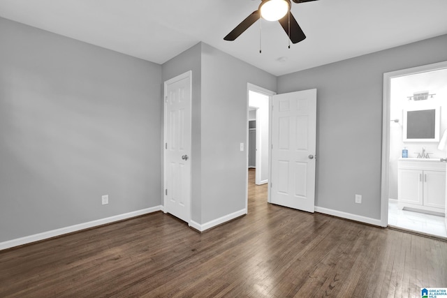 unfurnished bedroom featuring sink, ensuite bath, dark wood-type flooring, and ceiling fan