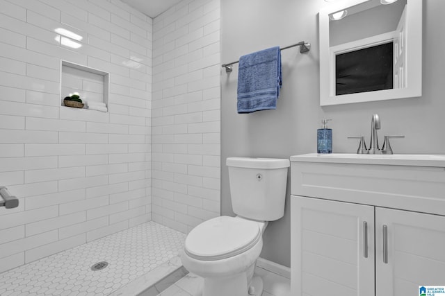 bathroom with vanity, toilet, and a tile shower