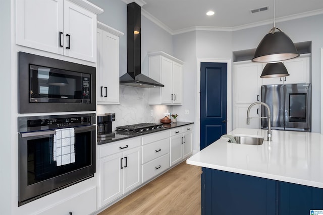 kitchen with dark countertops, visible vents, hanging light fixtures, appliances with stainless steel finishes, and wall chimney exhaust hood