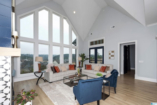 living area with light wood-style floors, baseboards, visible vents, and high vaulted ceiling