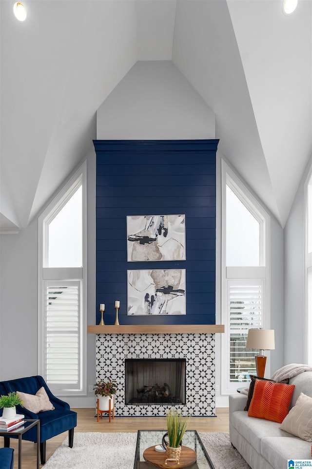 living area with vaulted ceiling, a fireplace, and wood finished floors