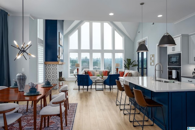 kitchen featuring hanging light fixtures, black appliances, a fireplace, and white cabinets