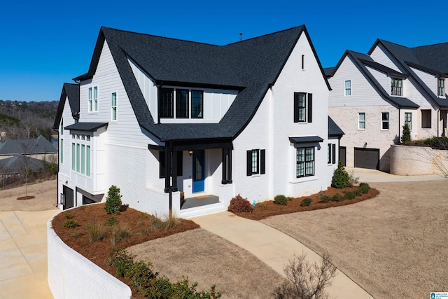 modern inspired farmhouse featuring a garage, concrete driveway, brick siding, and roof with shingles