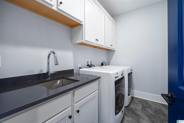 washroom with cabinet space, washing machine and dryer, baseboards, and a sink