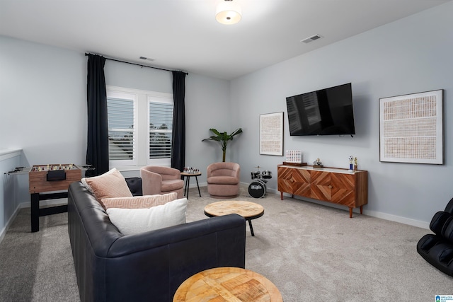 living area with baseboards, visible vents, and light colored carpet