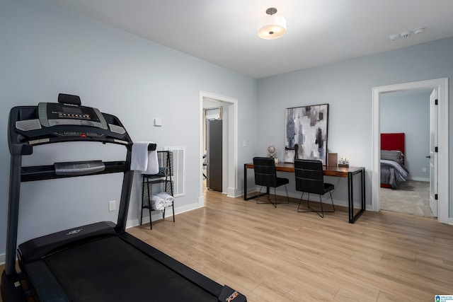 workout area with light wood-style flooring, visible vents, and baseboards