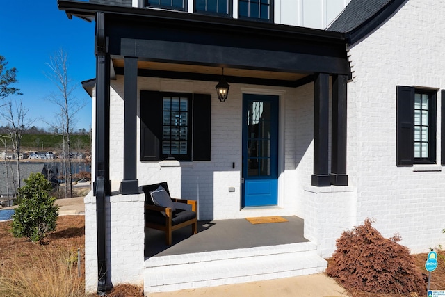 view of exterior entry with covered porch and brick siding