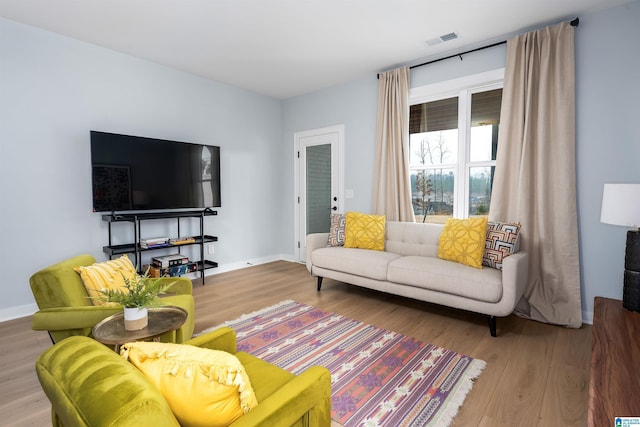 living area featuring wood finished floors, visible vents, and baseboards