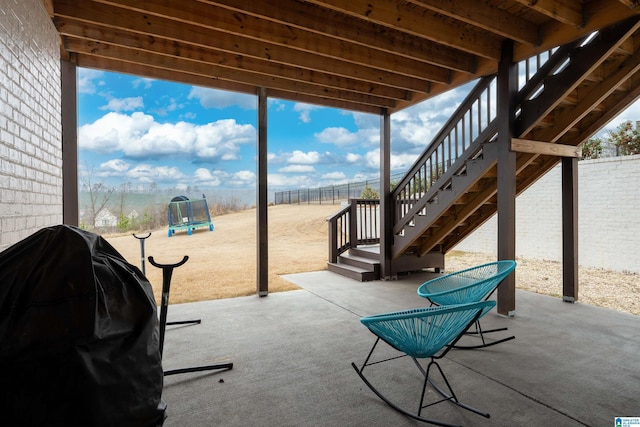 view of patio / terrace with a trampoline, fence, area for grilling, and stairs