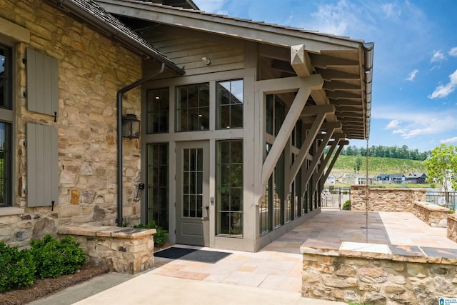 view of exterior entry featuring stone siding and a gate