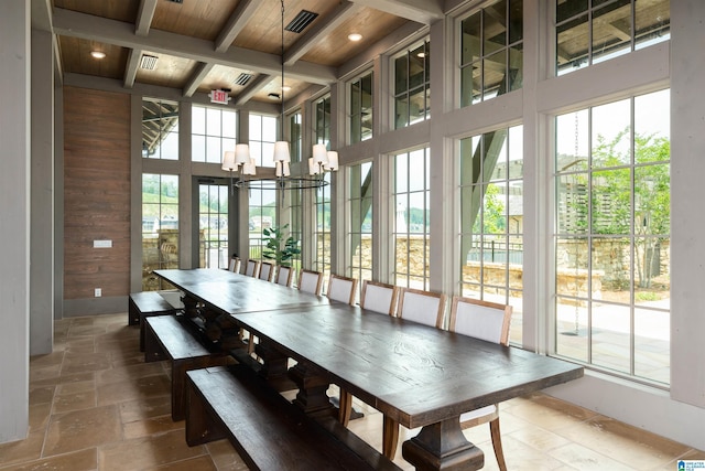 interior space featuring wood walls, a wealth of natural light, beamed ceiling, stone tile flooring, and an inviting chandelier