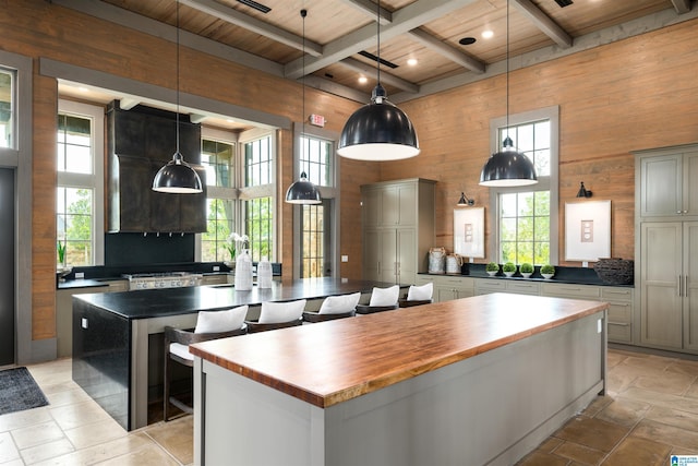 kitchen featuring a large island, beamed ceiling, stone tile flooring, and wooden walls