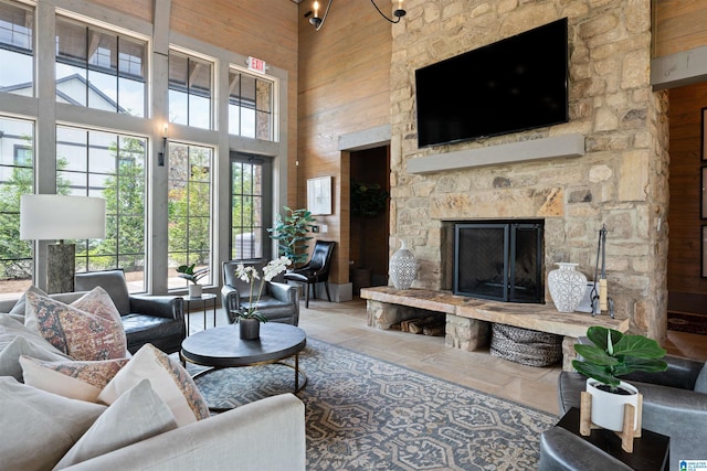 living room with a fireplace, wooden walls, and a towering ceiling