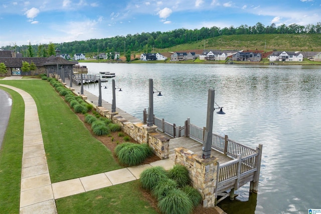 view of dock featuring a lawn, a water view, and a residential view