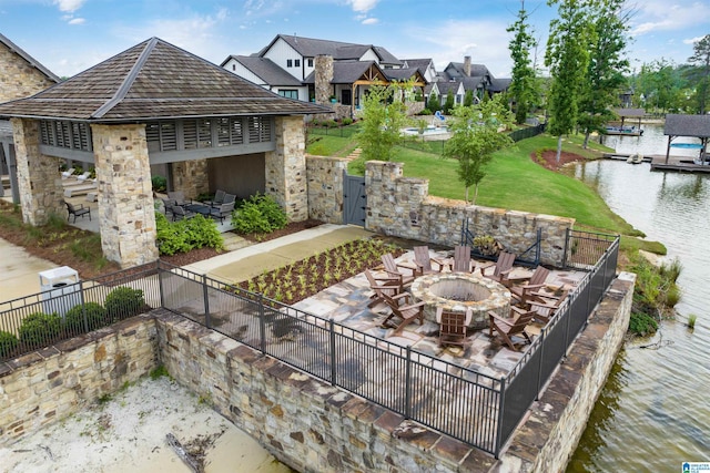 view of patio / terrace featuring a residential view, a water view, fence, and a fire pit