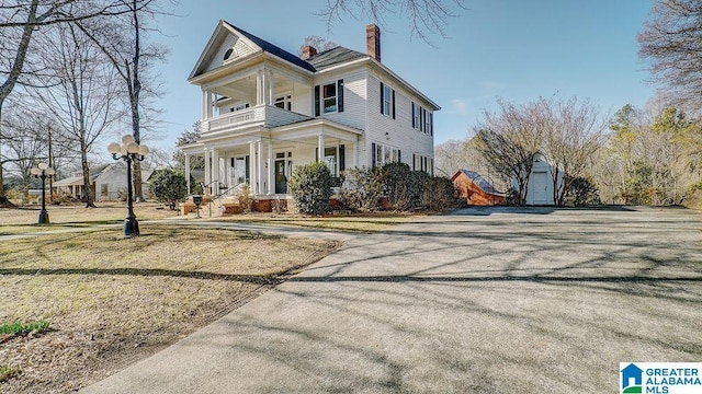 greek revival inspired property with a shed, a balcony, and a porch