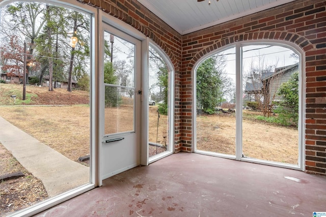 doorway featuring brick wall and concrete floors