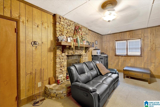 living room featuring a stone fireplace, light colored carpet, and wood walls