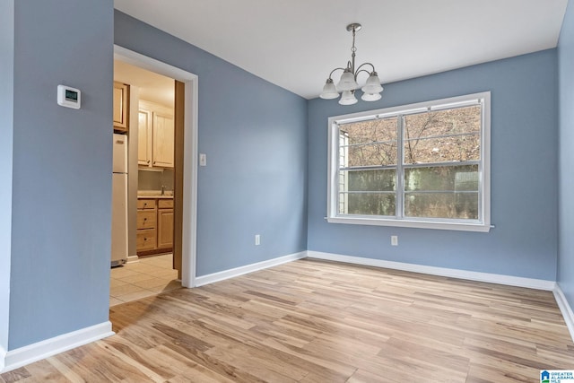 unfurnished dining area with light hardwood / wood-style floors and a notable chandelier