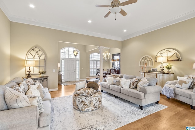 living room featuring ornamental molding, ceiling fan with notable chandelier, and light hardwood / wood-style flooring