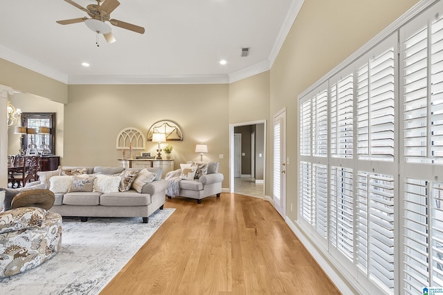 living room with crown molding, plenty of natural light, ceiling fan, and light hardwood / wood-style flooring