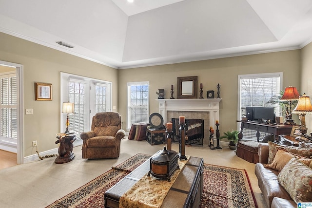 carpeted living room featuring a tray ceiling, crown molding, a fireplace, and a healthy amount of sunlight