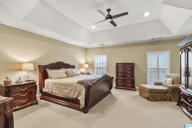 bedroom with a tray ceiling, light carpet, and multiple windows