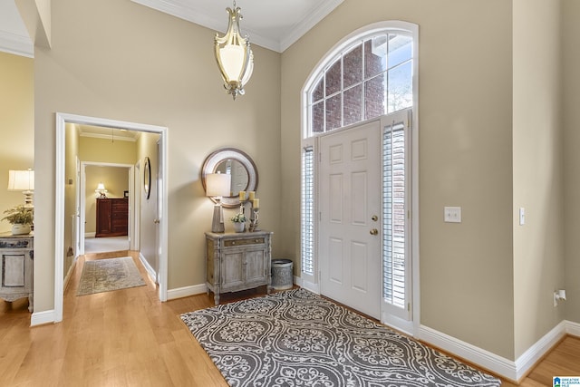 entrance foyer with a high ceiling, ornamental molding, and light wood-type flooring