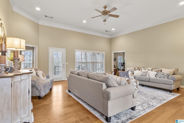 living room featuring a wealth of natural light, light hardwood / wood-style flooring, and ornamental molding