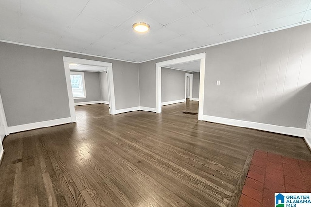 empty room with ornamental molding and dark hardwood / wood-style floors