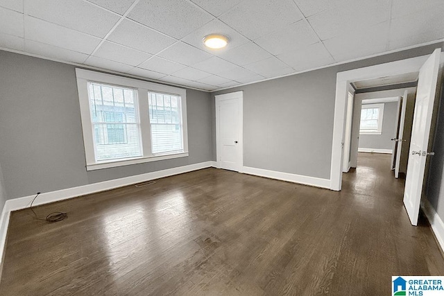 unfurnished room with dark hardwood / wood-style flooring and a drop ceiling