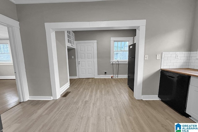 kitchen with light hardwood / wood-style flooring, wooden counters, white cabinetry, black appliances, and a healthy amount of sunlight