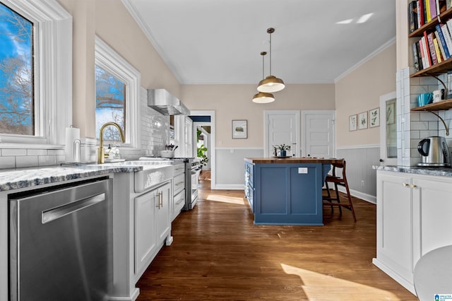 kitchen with appliances with stainless steel finishes, hanging light fixtures, a breakfast bar area, white cabinets, and a center island