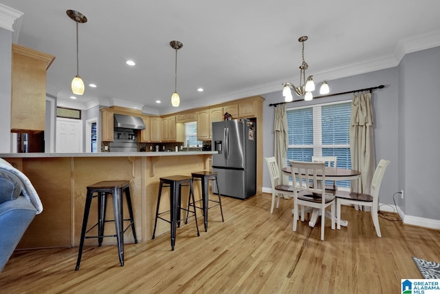 kitchen featuring stainless steel fridge, wall chimney exhaust hood, kitchen peninsula, light brown cabinets, and light hardwood / wood-style flooring