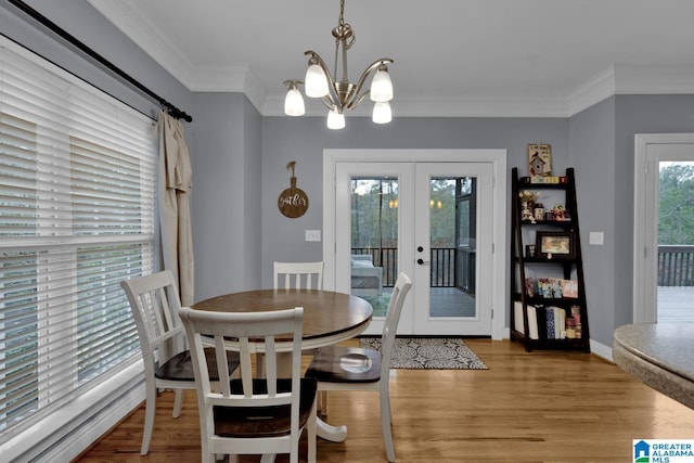 dining area featuring ornamental molding, french doors, a chandelier, and light wood-type flooring