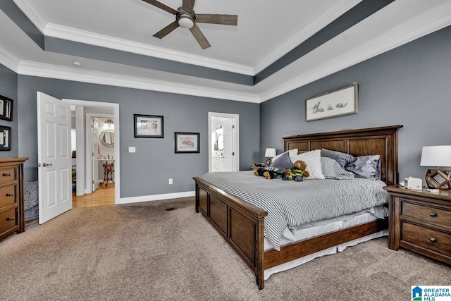 bedroom with a raised ceiling, ornamental molding, connected bathroom, and light colored carpet