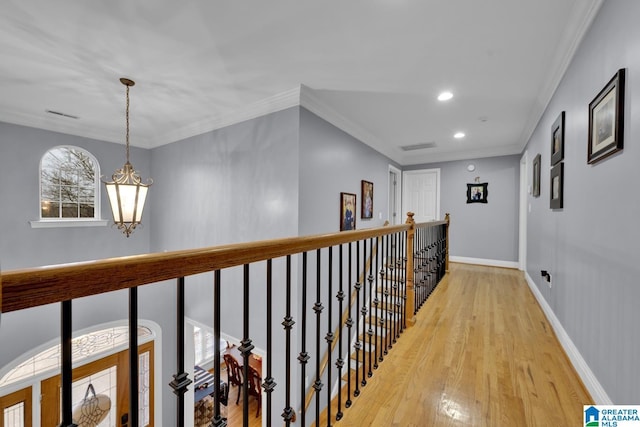 corridor with light hardwood / wood-style flooring, ornamental molding, and a chandelier