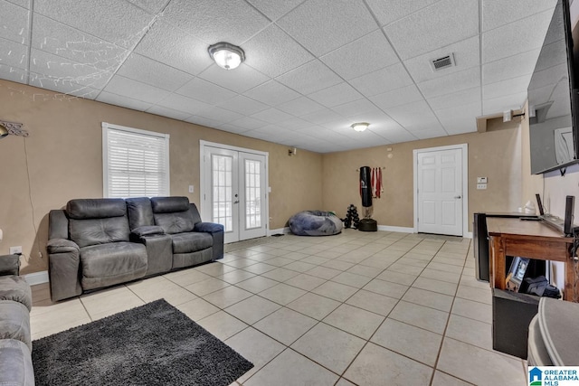 tiled living room with a drop ceiling and french doors