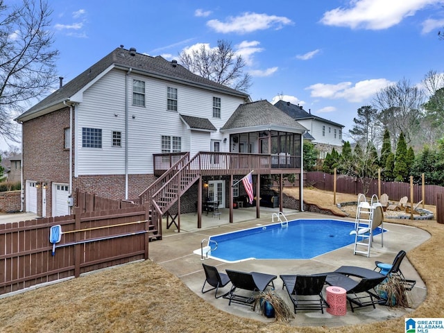 view of pool featuring a wooden deck, a sunroom, and a patio